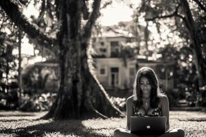 A woman sitting on the grass with a laptop photo