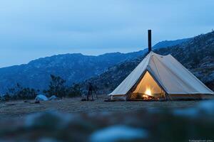 A tent with a fire in it sitting on a hill photo