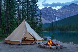A tent is set up near a lake with mountains in the background photo