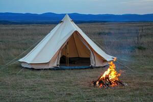 A tent with a fire in the middle of a field photo