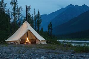 A tent with a fire lit in front of a mountain photo