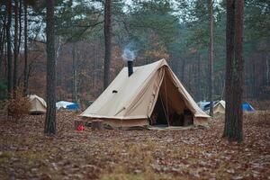 A tent in the woods with a fire photo