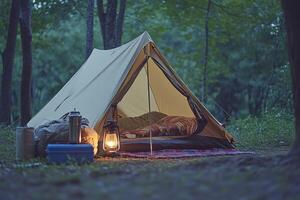 A tent in the woods with a lantern and a blanket photo