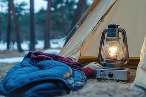 A camping lantern and a sleeping bag next to a tent photo
