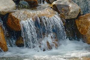 A man sitting on a rock next to a waterfall photo