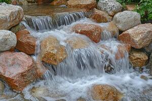 A waterfall flowing over rocks in a garden photo