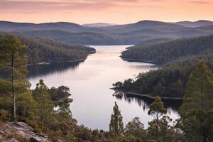 A lake surrounded by trees and hills at sunset photo