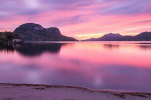 A purple sky and a lake with mountains in the background photo