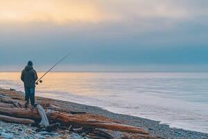 A man standing on the beach with a fishing rod photo
