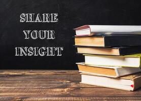 A stack of books with the words share your insight written on top photo