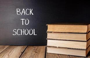 A stack of books is on a wooden table with the words back to school photo