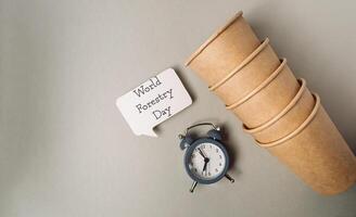 Clock sits on a table next to a stack of paper cups photo