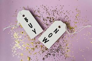 Two tags with the words buy and now are hanging from a string photo