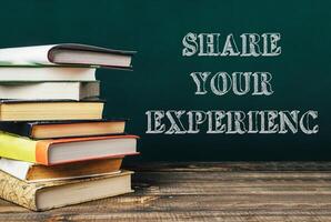 Stack of books with the words share your experience written on top photo