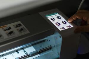 User interacts with a precise plotter for cutting hydrogel film in a modern workspace during the day photo