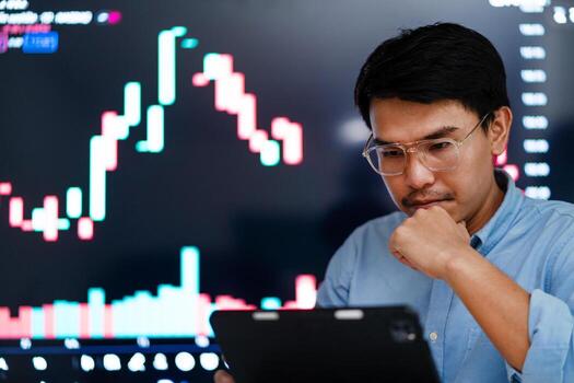 un hombre es mirando a un computadora pantalla con un grafico en él. él es vistiendo lentes y él es profundo en pensamiento foto