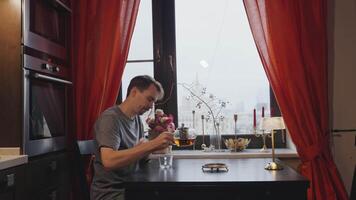 Man pouring tea while sitting at a table by the window video