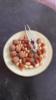 A plate of nuts on a table with a pair of tongs photo