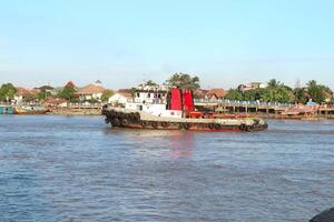 tugboat pulling a heavily laden coal barge sailing on the Musi River. photo