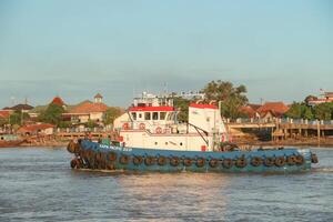 tugboat pulling a heavily laden coal barge sailing on the Musi River. photo