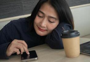Woman face sleep down at the table, coffee cup on the table and tablet her look at mobile phone while using social media,Relax vacation lifestyle concepts photo