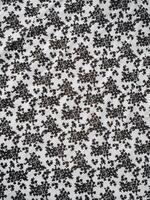 The pattern and background of the fabric is white with a small black flower motif photo