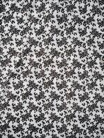 The pattern and background of the fabric is white with a small black flower motif photo