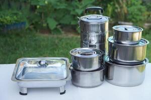 Set of stainless steel cookware and kitchen utensils. Pots, tray and tiffin box for containing food. Concept, preparing equipment for eating out. Picnic. photo