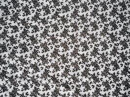 The pattern and background of the fabric is white with a small black flower motif photo