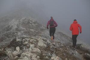 trail running couple man and woman running on a mountain path photo