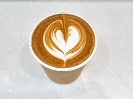 top view beauty white foam design couple flower heart in brown paper cup of coffee on isolated white background. save earth for use recycle container. photo