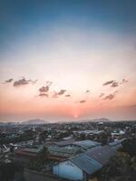 Sunset over a city with buildings and hills photo