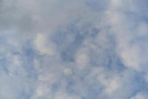 A plane flying through the sky with some clouds photo