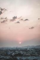 The sun sets over a city with a few buildings photo
