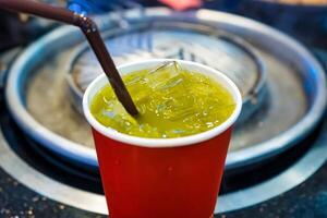 Cool and Refreshing Iced Green Tea in a Red Cup with Ice Cubes photo