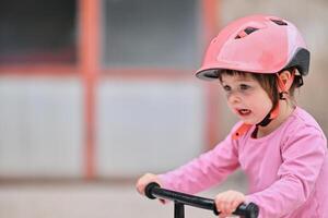 A little girl, dressed in a cute outfit and wearing a helmet, excitedly learning to ride her bike for the first time, filled with joy and determination. photo