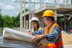 Engineering and architecture concept, Team engineers checking blueprint and planning project working outdoors building side on a worksite, Engineers having meeting regarding new construction phase. photo