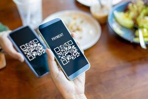 Hands holding mobile phone, Hand using mobile phone application to scan QR code, Qr code payment or cashless technology concept, Coffee shop accepting digital pay without money, Meaningless QR code. photo