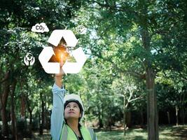 Woman engineer wearing a safety helmet show the symbol of recycling, waste reduction, pollution reduction and environmental conservation, Ready to use technology to work with digital at renewable. photo