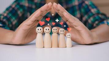 Human hands are choosing life insurance and investing to reduce risk, Wooden dolls with a plus sign and red heart represents protection, Health care planning, Concept of insurance and protection. photo