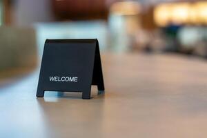 Black sign there is a message saying Welcome with a copy space is placed on a cement table for Enter the text of restaurant, store, or cafe. photo