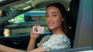 Smiling happy Caucasian driver school student female woman girl car owner sitting inside automobile window looking camera smile showing driving license courses pass exam rental service buying vehicle video