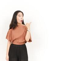 Presenting and Pointing Side Product Using Thumb Of Beautiful Asian Woman Isolated On White Background photo