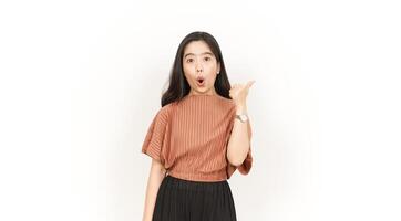 Showing and Pointing Product With Thumb Of Beautiful Asian Woman Isolated On White Background photo