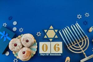 Jewish holiday Hanukkah concept. Frame of traditional jelly donuts and menorah on dark blue background photo
