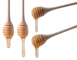 Flowing drops of yellow honey from a wooden stick on a white isolated background photo