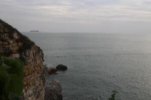 A rocky cliff overlooks the ocean photo