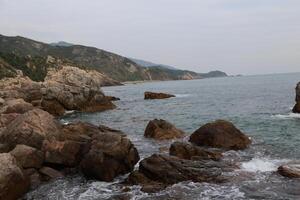 A rocky coastline with large rocks, the sea is calm and blue in color photo