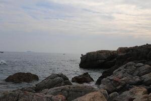 A rocky shoreline with a calm ocean in the background photo