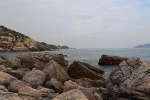 A rocky shoreline with a large body of water in the background photo